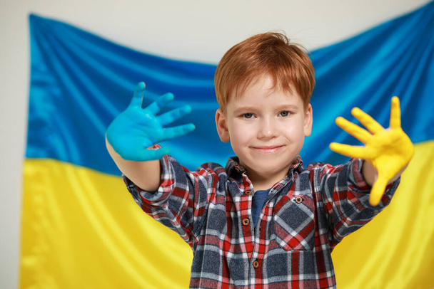 Little boy with painted hands near Ukrainian flag. Love Ukraine concept - Fotó, kép