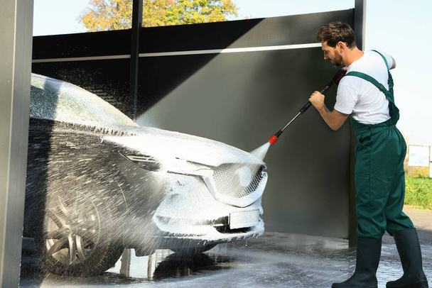 Worker washing auto with high pressure water jet at outdoor car wash - Foto, Imagen