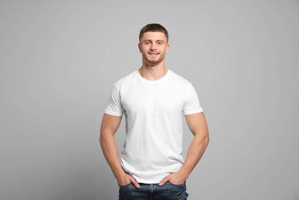 Man wearing white t-shirt on light grey background. Mockup for design - Photo, image