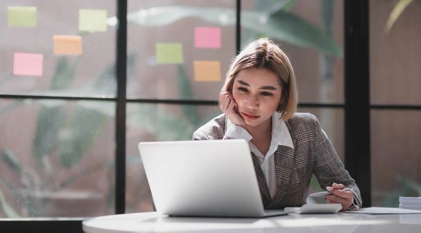 Aziatische zakenvrouw zijn ernstig op het werk waardoor hoofdpijn gestrest met documenten met een laptop op kantoor... - Foto, afbeelding