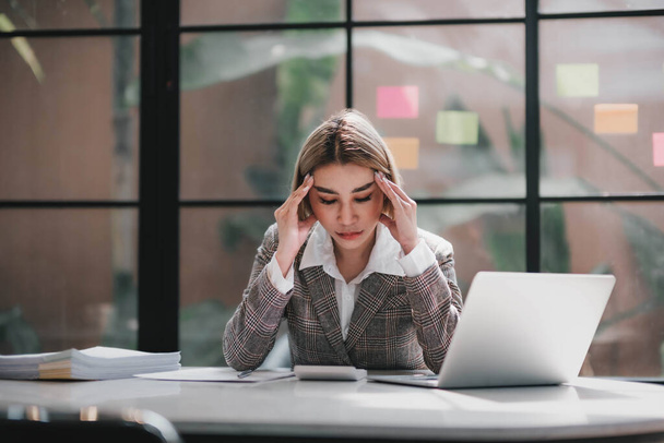 Azjatyckie bizneswoman są poważne w pracy powodując ból głowy zestresowany dokumentów z laptopem w biurze... - Zdjęcie, obraz