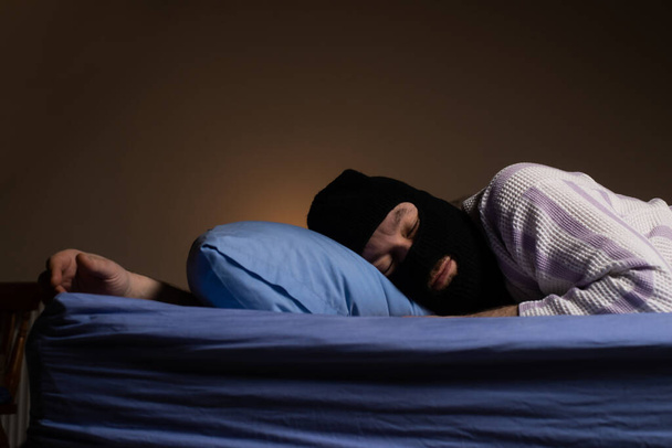 The robber in the mask lies in bed and sleeps. The thief is tired. Night adventure dreams playful concept. - Foto, Imagem