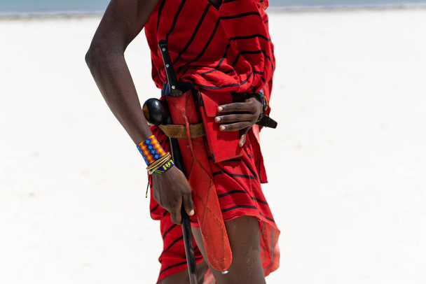 На этой увлекательной фотографии племенная рука масаи изображена в замысловатых деталях, демонстрируя красивый и красочный браслет, который представляет традиционную культуру Занзибара, Танзании в Африке. - Фото, изображение