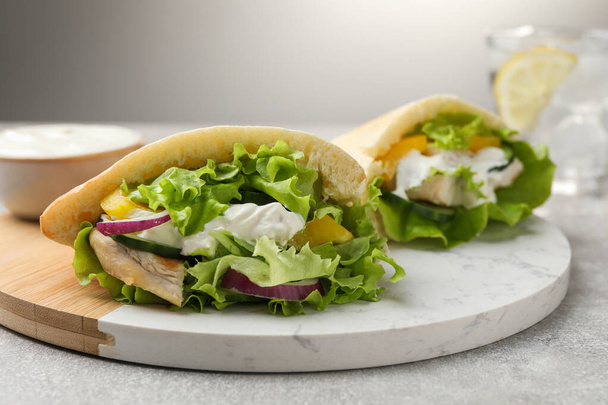 Delicious pita sandwiches with chicken breast and vegetables on light gray table, closeup - Photo, image