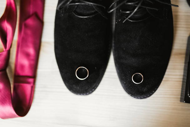 Set of mans fashion shoes with two golden wedding rings. - Foto, imagen