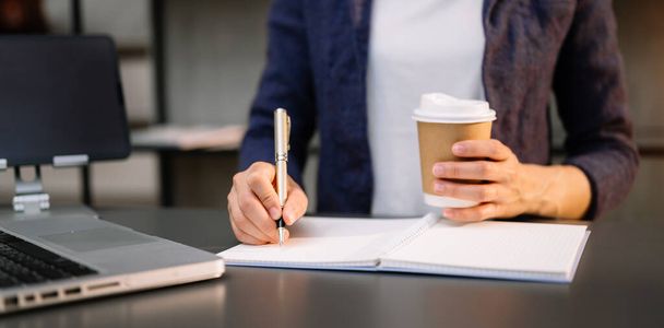 Businesswoman writing a note with coffee in office - 写真・画像
