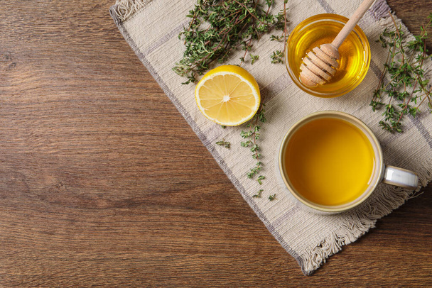 Aromatic herbal tea with thyme, honey and lemon on wooden table, top view. Space for text - Zdjęcie, obraz