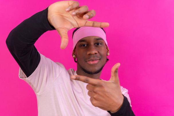 Black ethnic man in pink clothes on a pink background, concept portrait, smiling - Foto, imagen