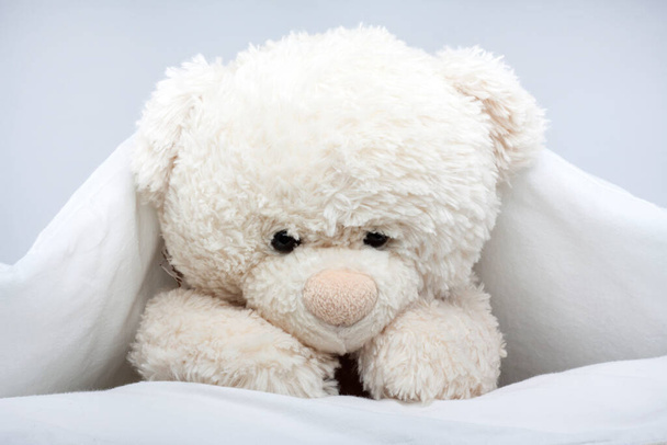 Jouet ours en peluche sous la couverture sur le lit - Photo, image