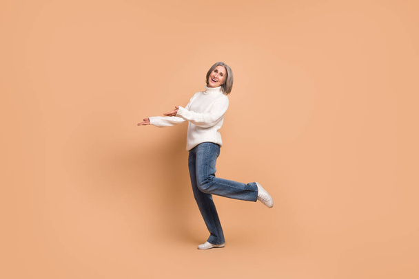 Full length photo of excited funny woman wear knitted pullover showing arms empty space isolated beige color background. - Фото, изображение