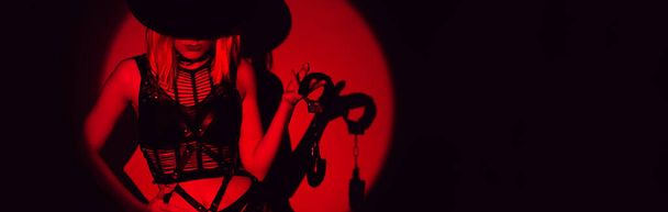 sexy slave girl in underwear and a hat holds handcuffs in hands. Concept of BDSM submissive woman. Panoramic wide horizontal photo for banner head cover - Фото, изображение