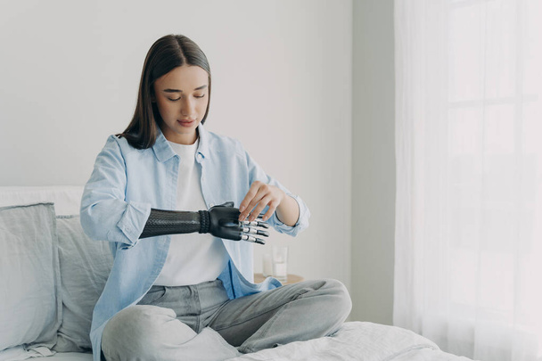 Upośledzona młoda kobieta ustawia bioniczne parametry protezy nerwów. Bionic ręka ma procesor chip i przyciski. Europejka dopasowuje sztuczne ramię. Rozwój innowacji. - Zdjęcie, obraz