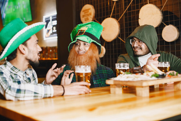 Guys and girl in green hats. Indians in a pub. St. Patricks Day celebration. - Fotografie, Obrázek