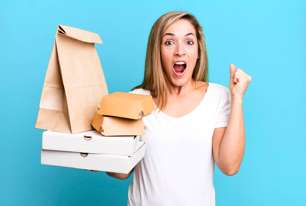 pretty blonde woman shouting aggressively with an angry expression. delivery take away food packages concept - Фото, зображення