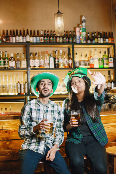 Guys and girl in green hats. Indians in a pub. St. Patricks Day celebration. - Zdjęcie, obraz