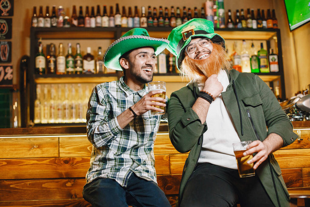 Guys and girl in green hats. Indians in a pub. St. Patricks Day celebration. - Foto, immagini