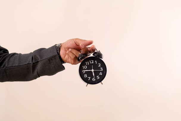 Close up photo of Asian muslim man's hand holding a clock. Breaking the fasting time concept in ramadhan - Foto, imagen