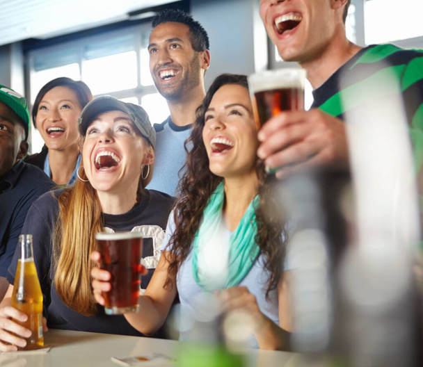 Ystävälliset juomat ja urheilutoiminta kulkevat käsi kädessä. Ystävät hurraavat suosikkijoukkueelle baarissa. - Valokuva, kuva