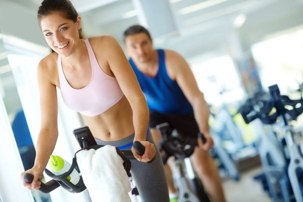 Spinning class gets my heart racing. A man and woman exercising in spinning class at the gym - Fotó, kép