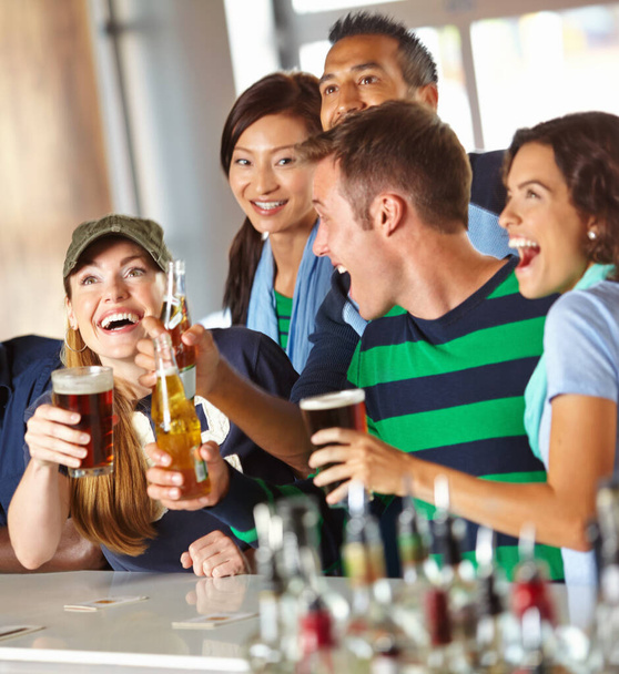 El no puede tener suficiente de deportes y bebidas. Un grupo de amigos emocionados animando a su equipo favorito en el bar - Foto, Imagen