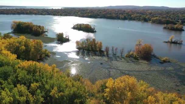 Drone powietrzny strzał panning od prawej do lewej nad rzeką Mille Iles z odbiciem słońca w wodzie i kolorowe drzewa jesieni - Materiał filmowy, wideo