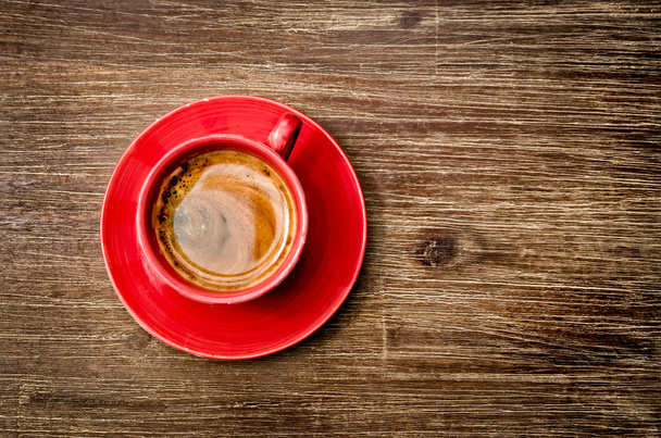 Blick auf Kaffee in roter Tasse auf hölzernem Vintagetisch - Foto, Bild