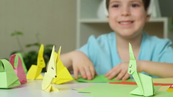 Νηπιαγωγείο με αυτιά κουνελιού nag κεφάλι κάνει Πάσχα χειροτεχνίες, origami ειδώλια των κουνελιών και καλάθια από χαρτί. - Πλάνα, βίντεο