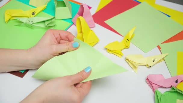 Оригами складывает фигурки пасхальных кроликов из бумаги, руки крупным планом - Кадры, видео