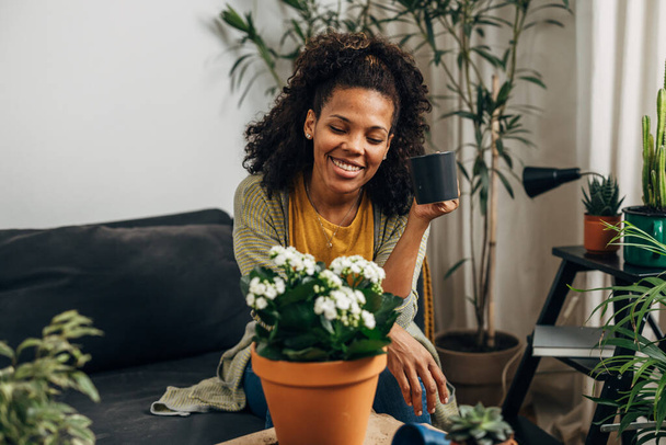 A beautiful mixed race woman enjoys looking at her houseplants - Foto, afbeelding