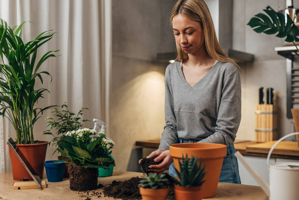 A cute Caucasian woman enjoys working with plants - Photo, Image