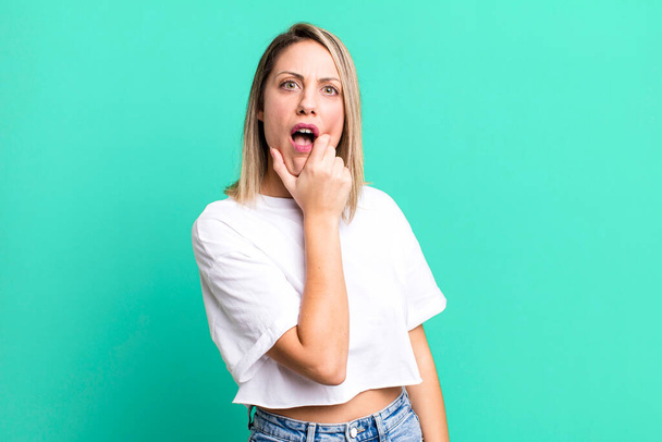 blonde adult woman with mouth and eyes wide open and hand on chin, feeling unpleasantly shocked, saying what or wow - Foto, Bild