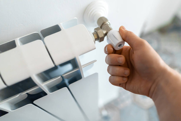 Чоловіча рука регулює термостат, щоб увімкнути обігрівач радіатора в домашніх умовах
. - Фото, зображення