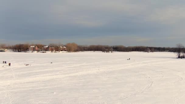 Літаючи з безпілотником, дуже повільно, над білим снігом, що покриває замерзлу річку в Сент-Естесі, показуючи людям льодову риболовлю - Кадри, відео