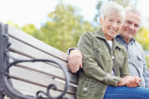 Profiter d'une pause bien méritée. Portrait d'un couple d'âge mûr assis sur un banc ensemble et souriant à la caméra - Photo, image