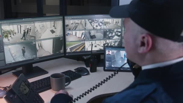 Офіцер служби безпеки контролює CCTV камери з розпізнаванням облич в офісі, використовує цифрові планшети і комп'ютери. Високотехнологічне програмне забезпечення з камерами спостереження, що відтворення на екранах. Концепція соціального захисту. - Кадри, відео