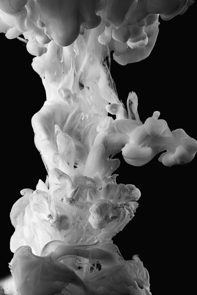 Ink dropped into the water and photographed while in motion. Paint swirling in water. Grey  and white cloud and smoke of paint in water isolated on black background. - Фото, изображение