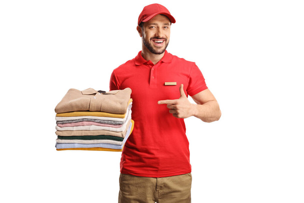 Laundry worker holding a pile of folded clothes and pointing isolated on a white backgroun - Foto, immagini