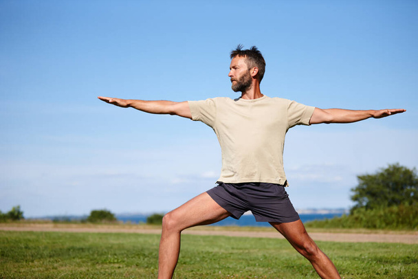 Si no te desafía, no te cambia. un hombre maduro guapo haciendo yoga al aire libre - Foto, imagen