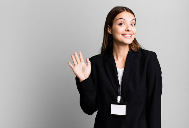 young pretty woman smiling happily, waving hand, welcoming and greeting you. businesswoman concept - Fotoğraf, Görsel