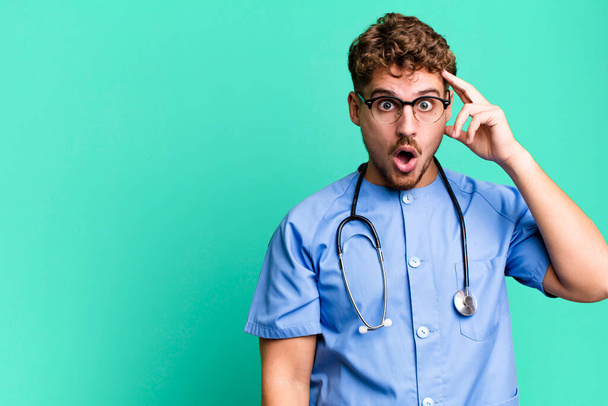 young adult caucasian man looking surprised, realizing a new thought, idea or concept. nurse concept - Photo, image