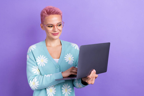 Portrait de joyeuse fille optimiste coiffure rose porter pull bleu regarder ordinateur portable communiquer isolé sur fond de couleur violette. - Photo, image
