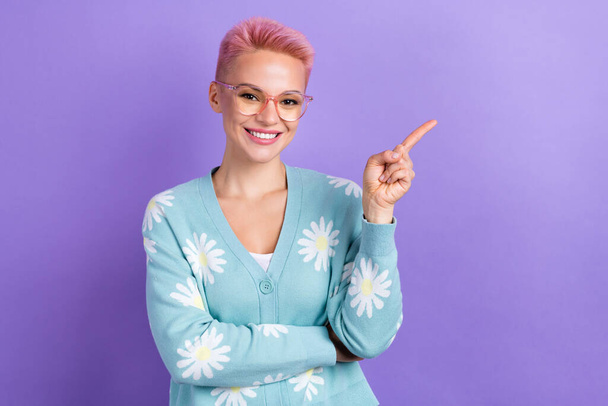Photo of satisfied optimistic woman with short hairstyle dressed blue cardigan indicating empty space isolated on purple color background. - Foto, imagen