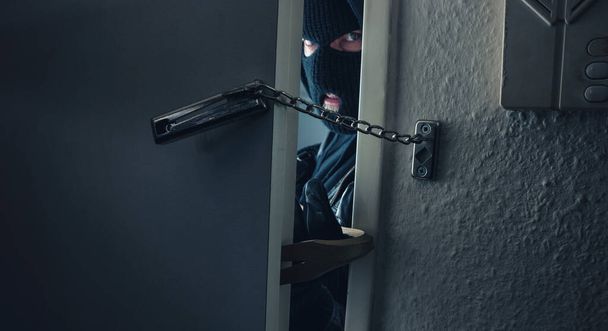 peligroso ladrón enmascarado con palanca irrumpiendo en la puerta de la casa de una víctima - Foto, Imagen