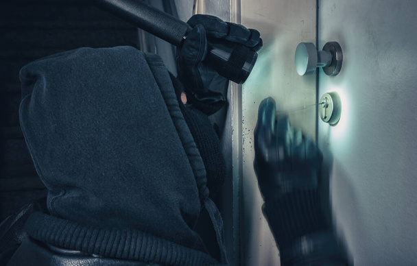Burglar with lock picking tools breaking into a house door - Фото, изображение
