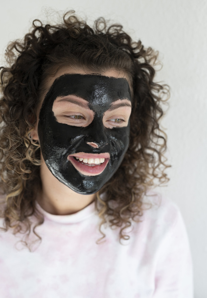 Young smiling woman with a facial mask at home, beaty treatment at home concept  - Foto, Bild