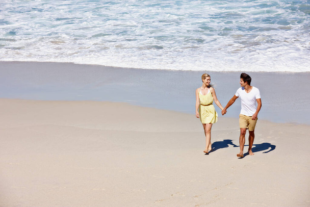 Its a summer of love. a happy young couple enjoying a romantic walk on the beach - Foto, Bild