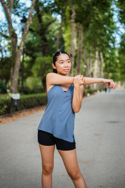Portrait of asian sport girl warming up in the park before jogging - Photo, Image