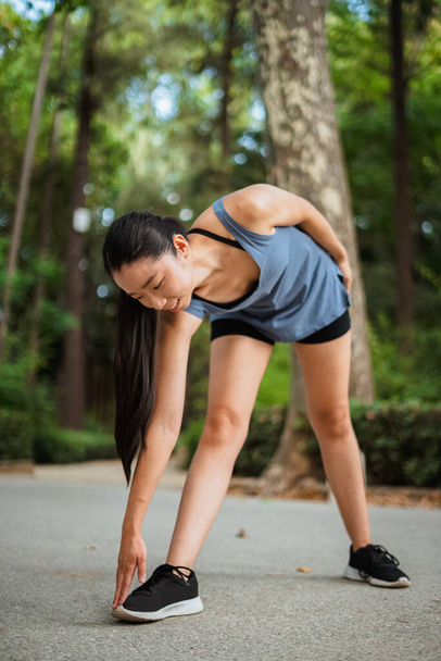 Asian fitness girl warming up in the park before jogging - Photo, image