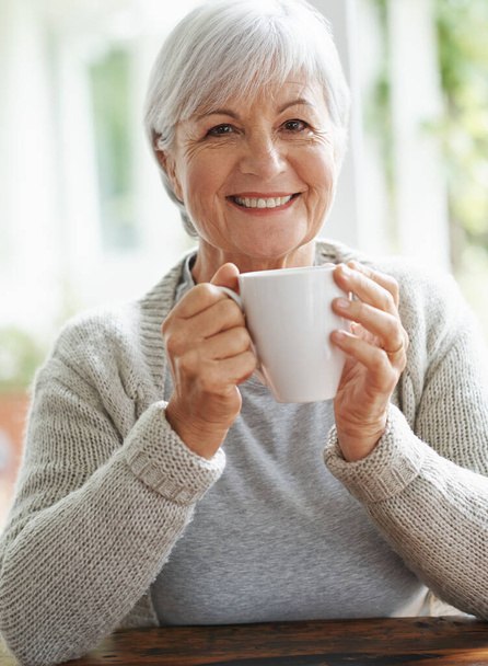 Comment abour une tasse de thé à la maison de grand-mère. Une heureuse femme âgée dégustant une tasse de café à sa table de cuisine - portrait - Photo, image