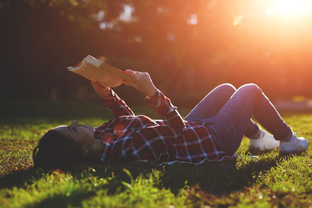 Woman lying on the grass and reading a book - Fotó, kép